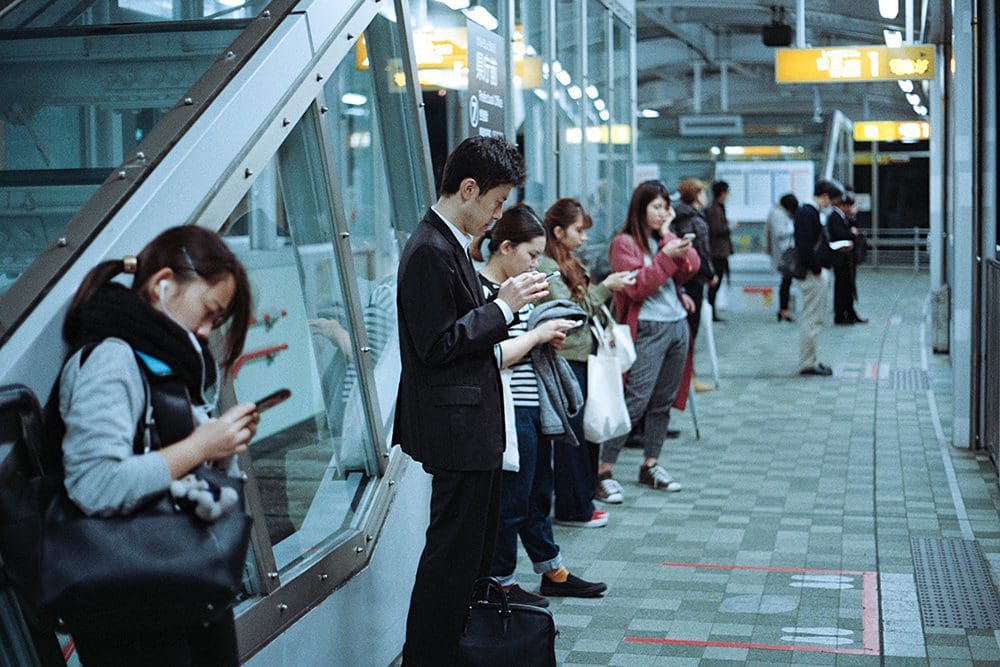 Group of people watching videos while waiting for a train