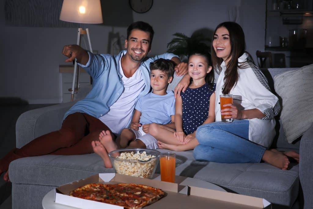 Happy family watching TV on sofa at night