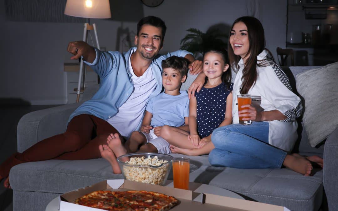 Happy family watching TV on sofa at night