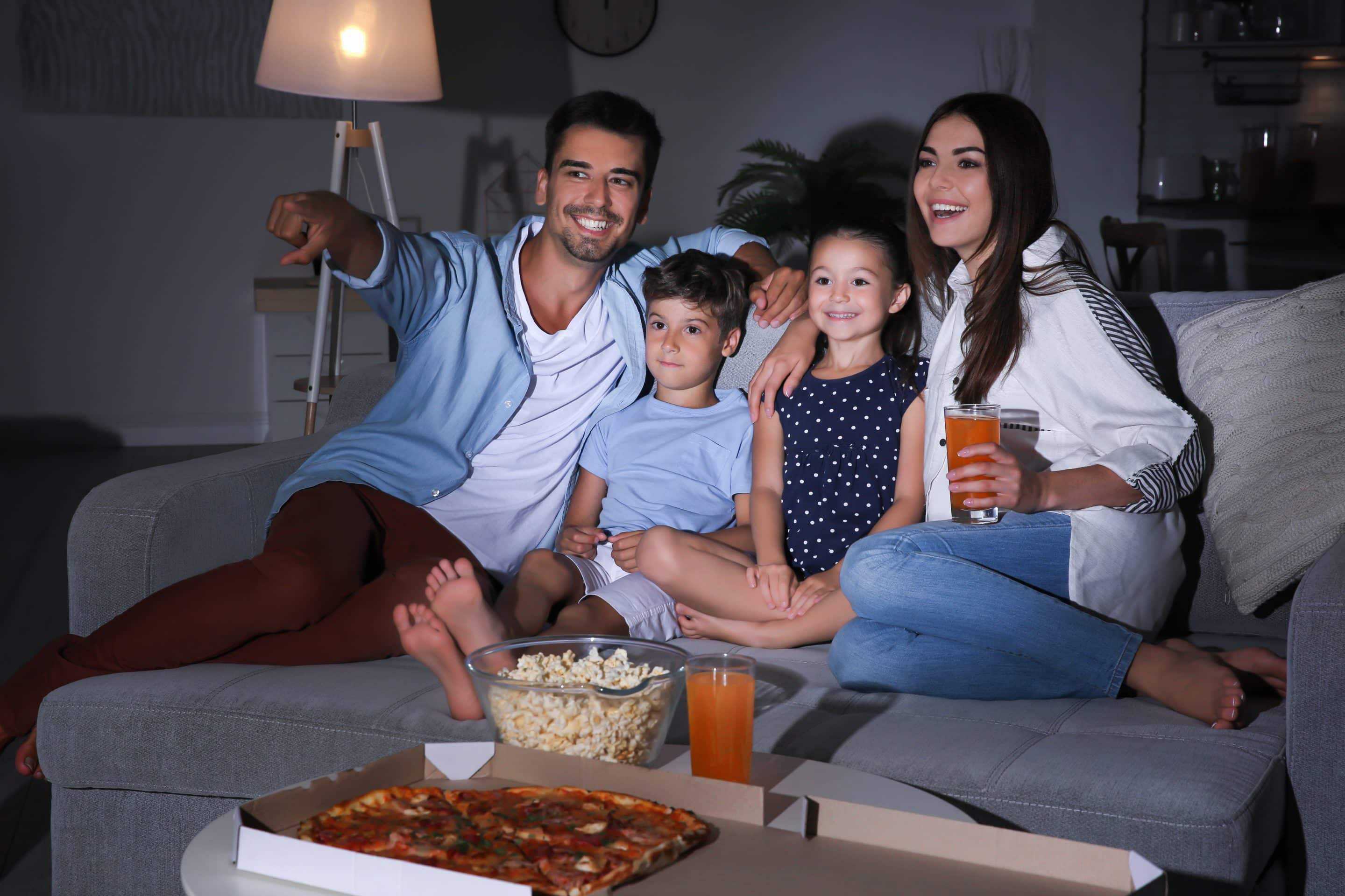 Happy family watching TV on sofa at night